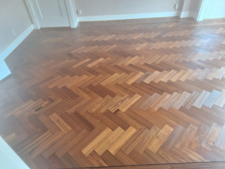 Teak visgraatvloer in een kamer met suitedeuren