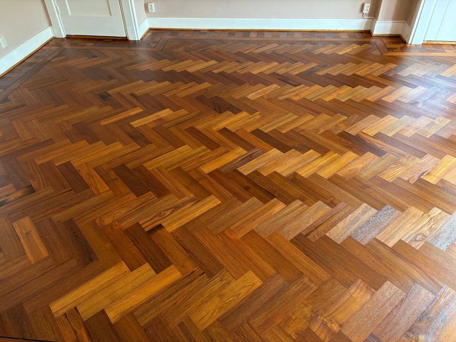 De teak visgraatvloer in het licht van het raam