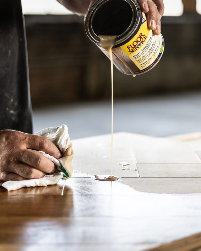 Hardwasolie wordt op een houten vloer aangebracht
