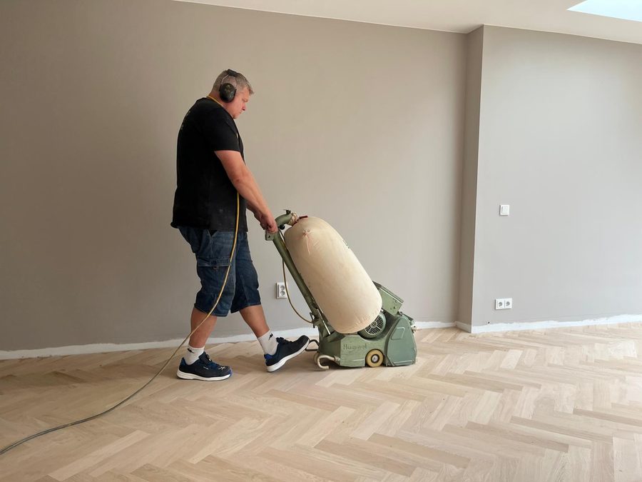 Houten visgraatvloer die geschuurd wordt