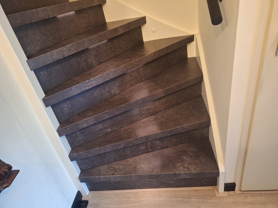 Dezelfde trap na de renovatie, afgewerkt met verlichting en een nieuwe leuning